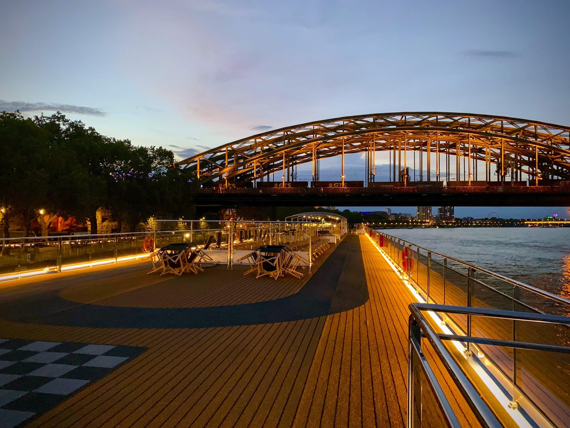 AmaSiena sun deck with floor lights on in Cologne, Germany with a bridge in the background
